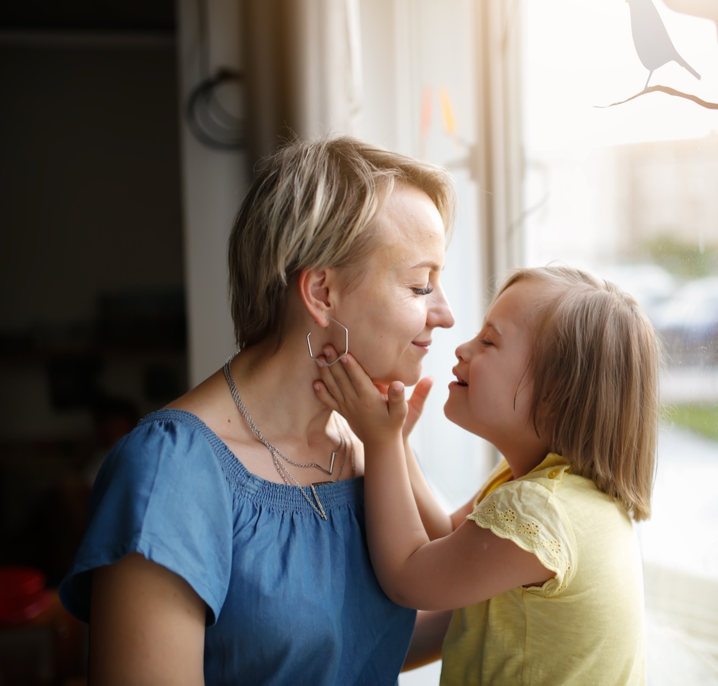 Mother and young daughter sharing a happy moment by a window